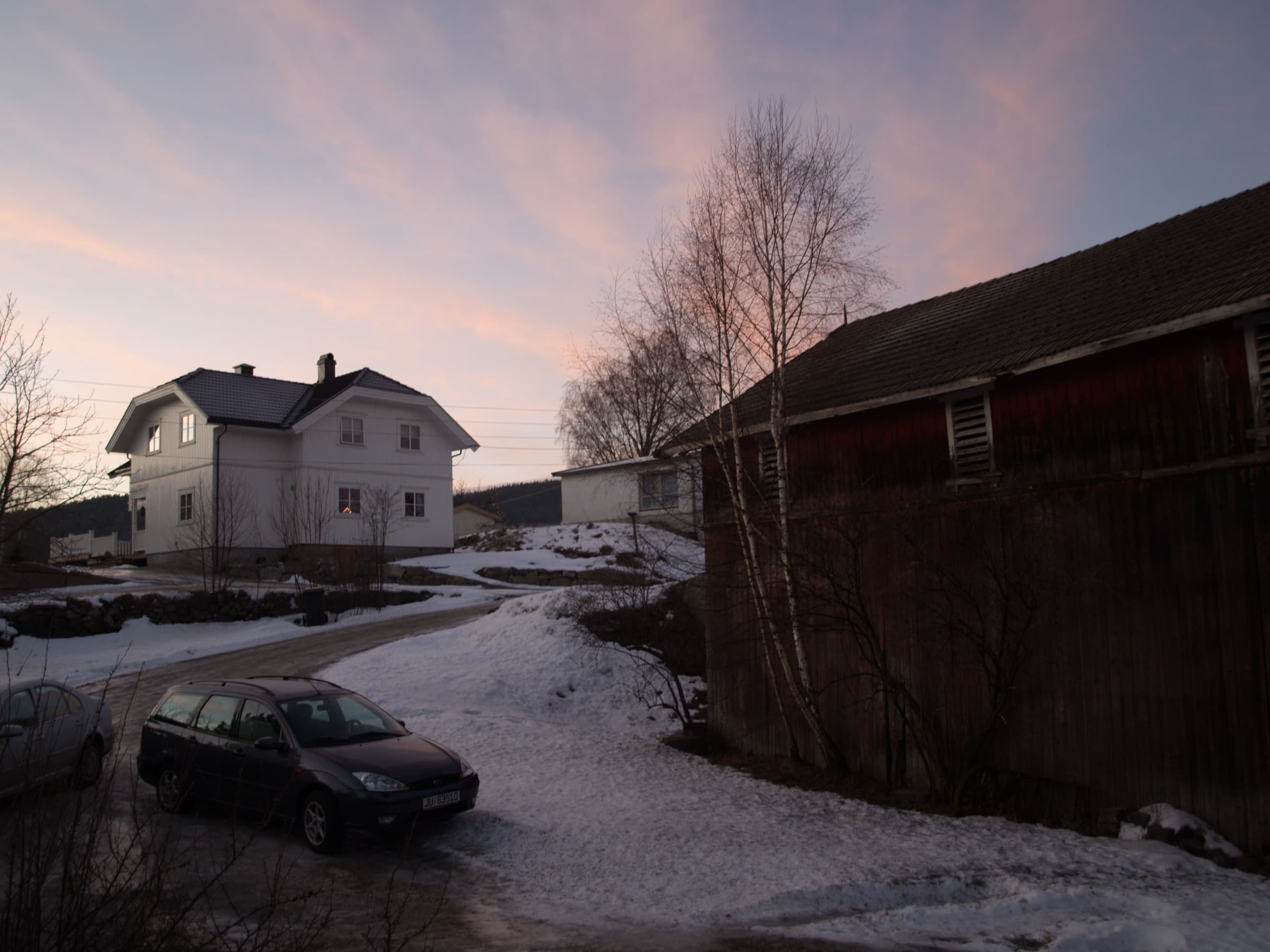 Åmot i vinterskumring med rosa himmel og lys i vinduene.